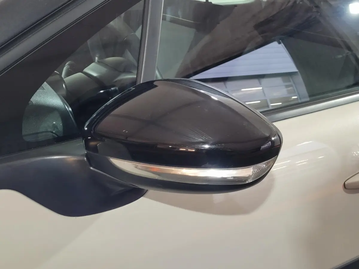 Rétroviseur noir avec clignotant intégré sur le côté gauche d'une Citroën C3 beige 2022.