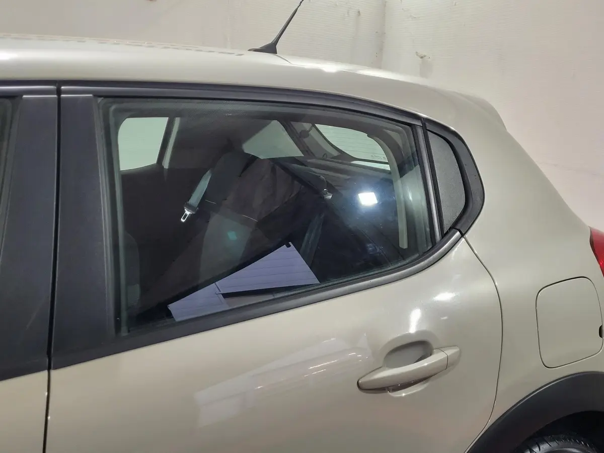Vue latérale côté gauche sur l'arrière d'une Citroën C3 beige avec poignée de porte et réservoir visible.