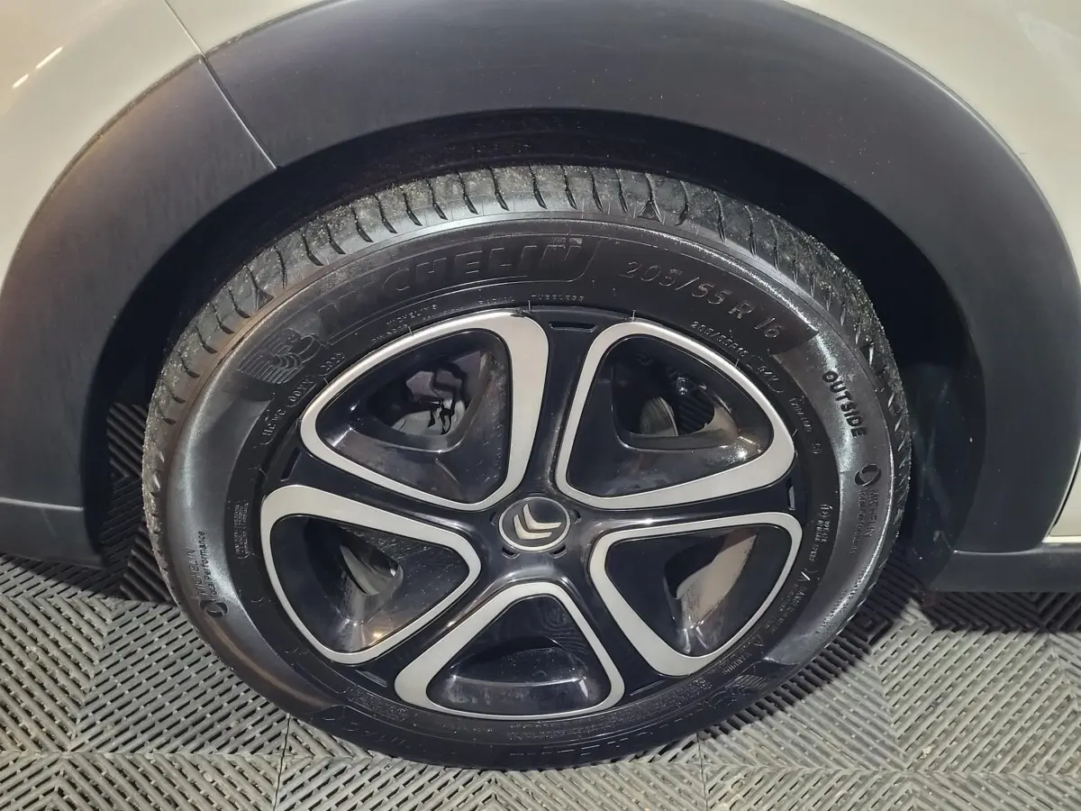 Gros plan sur la roue avant droite de la Citroën C3 beige 2022 avec jante noire et argentée au design moderne.