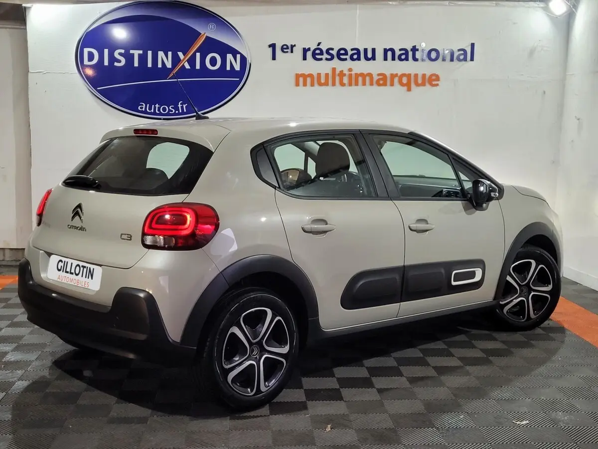 Citroën C3 beige vue 3/4 arrière droit, avec protections latérales noires et jantes alliage distinctives.