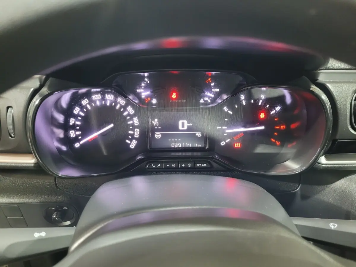 Vue rapprochée du tableau de bord numérique de la Citroën C3 beige, affichant la vitesse à 0 km/h et le compteur kilométrique.