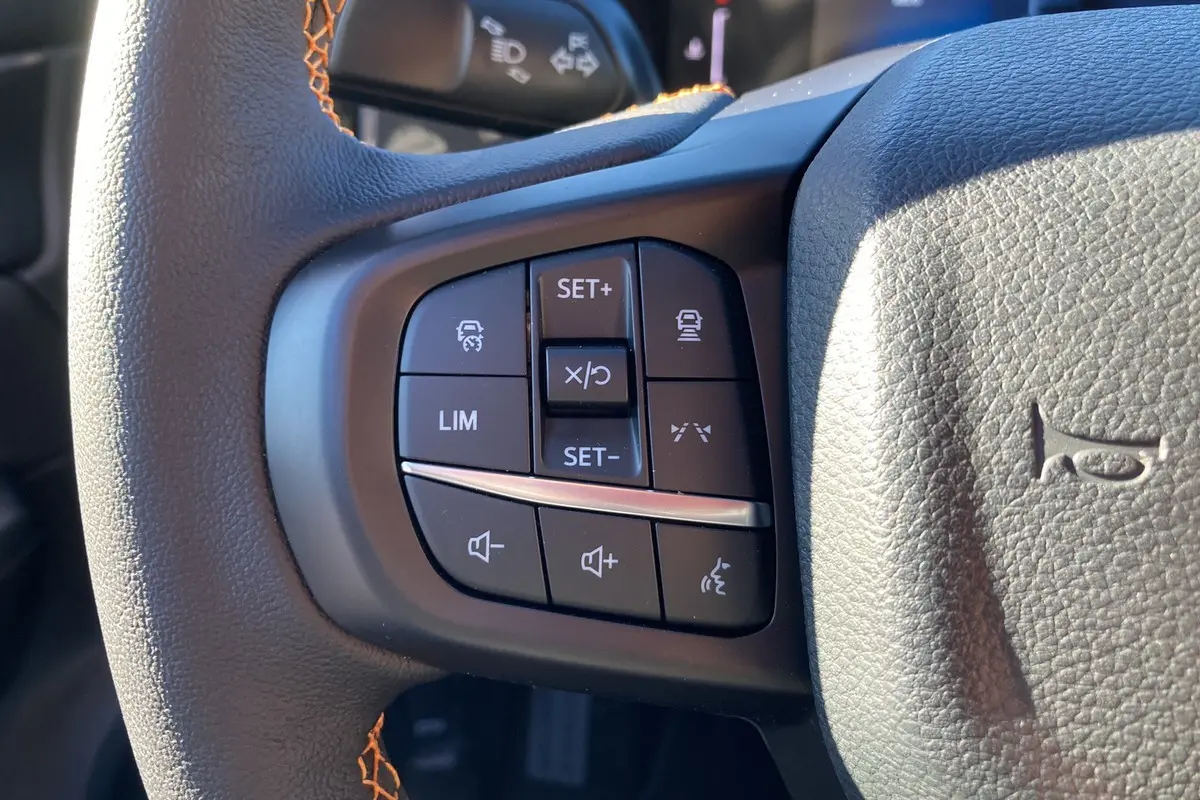 Gros plan sur les commandes multifonctions à gauche du volant cuir du Ford Ranger Wildtrak blanc glacier 2026.