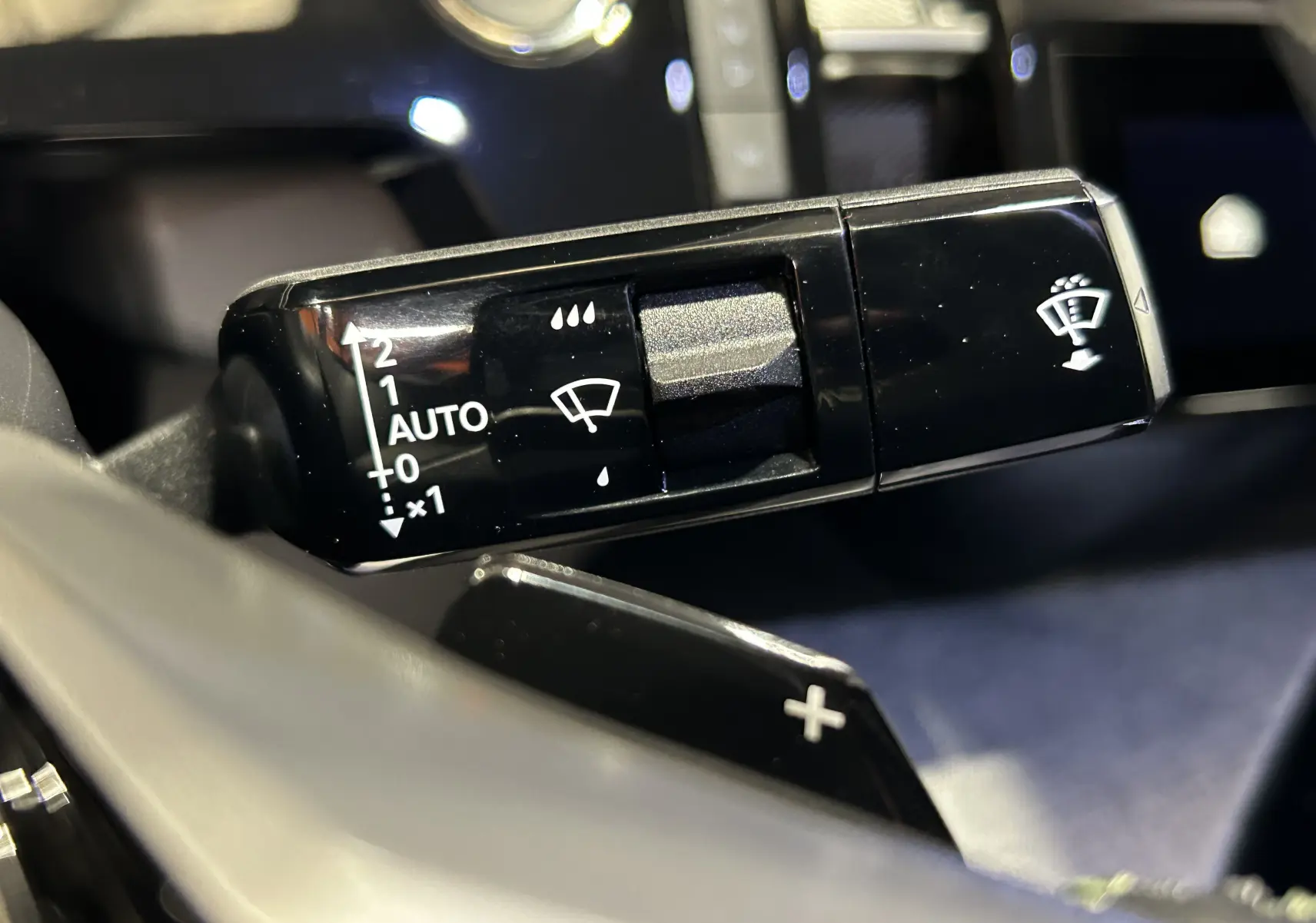 Gros plan sur la commande d’essuie-glace du Peugeot 3008 blanc Okenite, avec réglages automatiques visibles.
