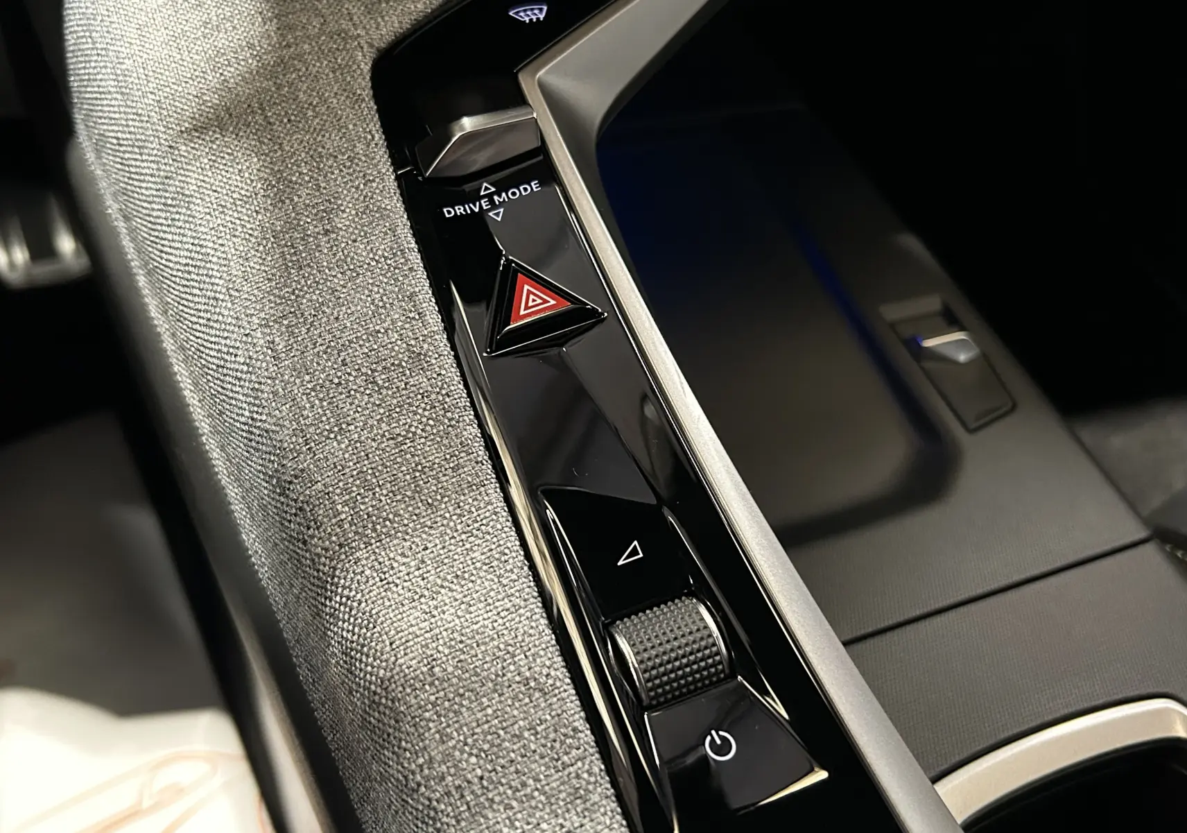 Gros plan sur la console centrale noire brillante du Peugeot 3008 blanc, avec boutons Drive Mode et alerte triangle rouge.