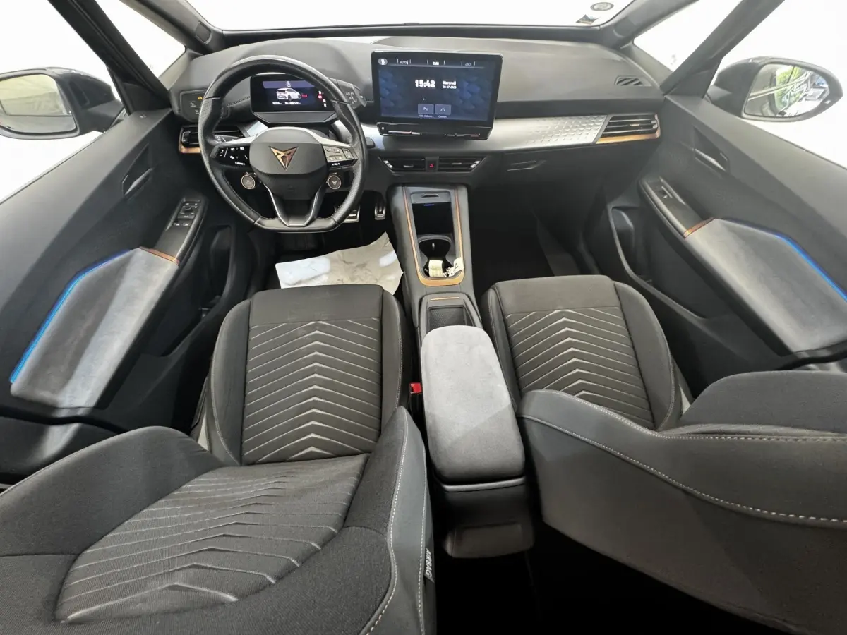 Intérieur avant du CUPRA BORN gris foncé 2023, vue du tableau de bord avec volant multifonctions et écran tactile central.