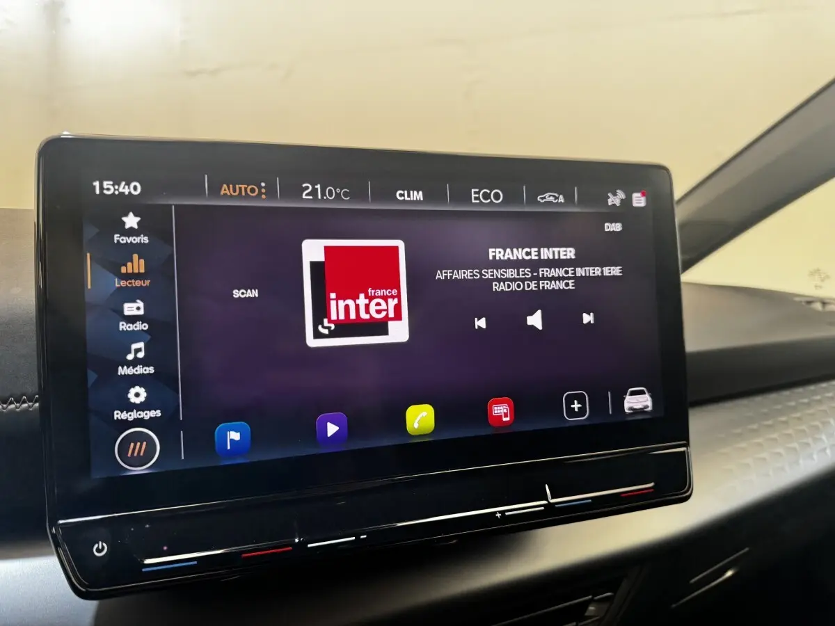 Écran tactile central de 12 pouces du tableau de bord d'une CUPRA Born 230ch gris foncé, affichant la radio France Inter.