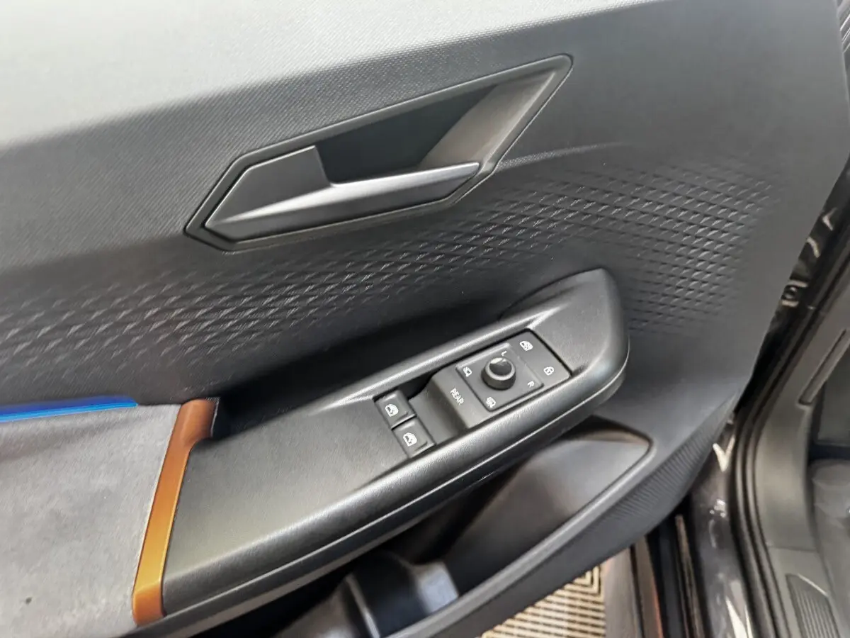 Vue rapprochée de la porte avant gauche gris foncé du CUPRA BORN avec commandes de vitres et poignée intégrée.