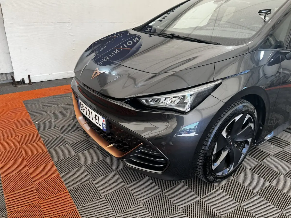 Vue 3/4 avant droit d'une CUPRA BORN gris foncé avec détails cuivrés et jantes noires distinctives.