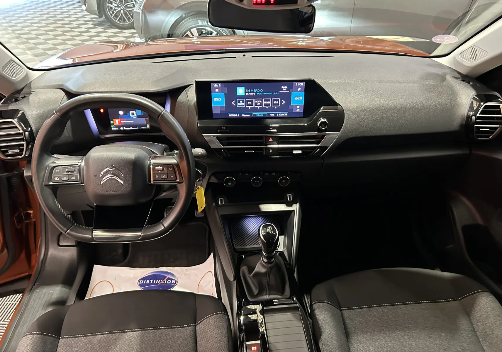 Vue intérieure avant de la Citroën C4 PureTech 100 Feel orange 2021 avec tableau de bord numérique et boîte manuelle.