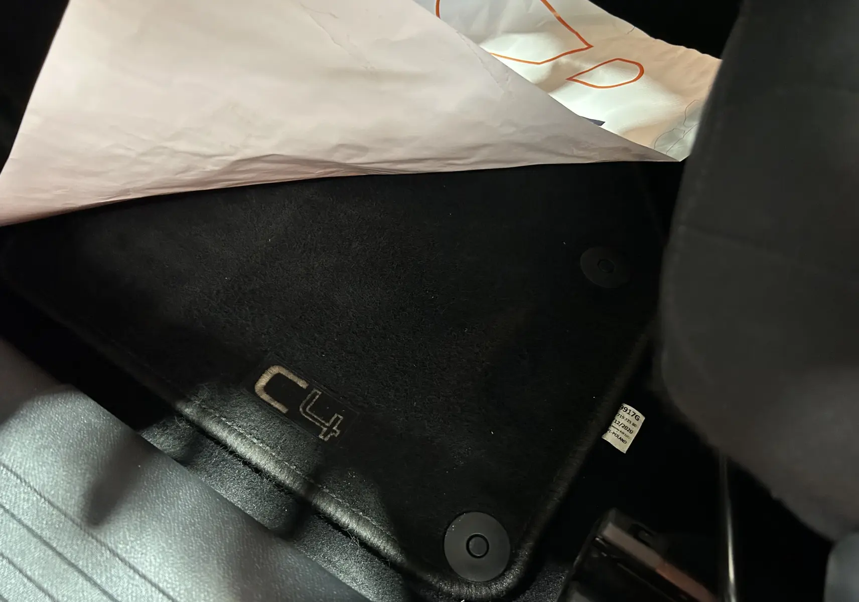 Tapis de sol noir avec logo C4 visible sous le siège avant d'une Citroën C4 orange PureTech 2021.