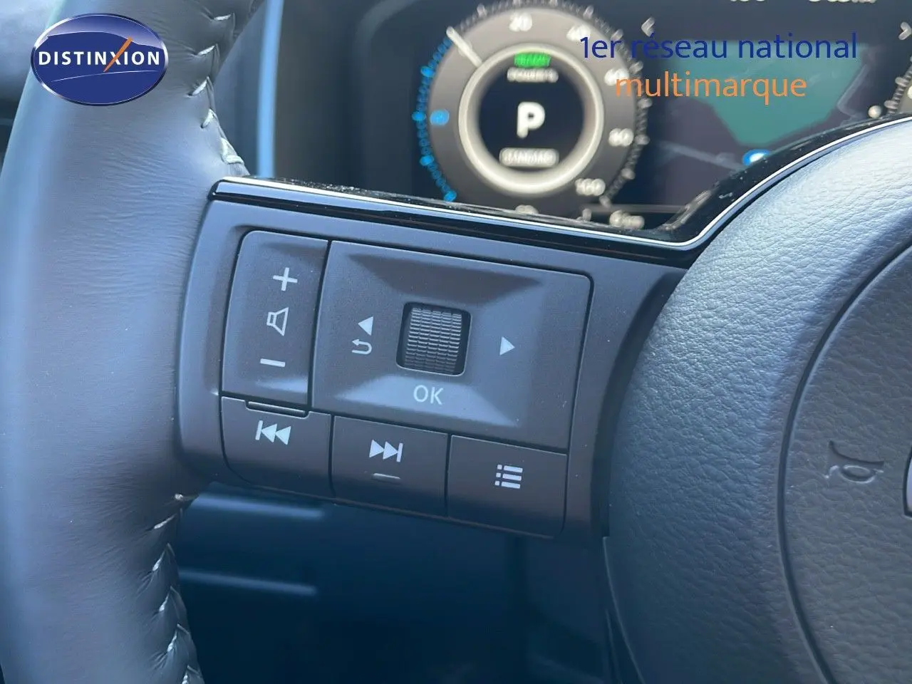Gros plan sur les commandes au volant du Nissan Qashqai 2025, finition N-Design, avec tableau de bord numérique en arrière-plan.
