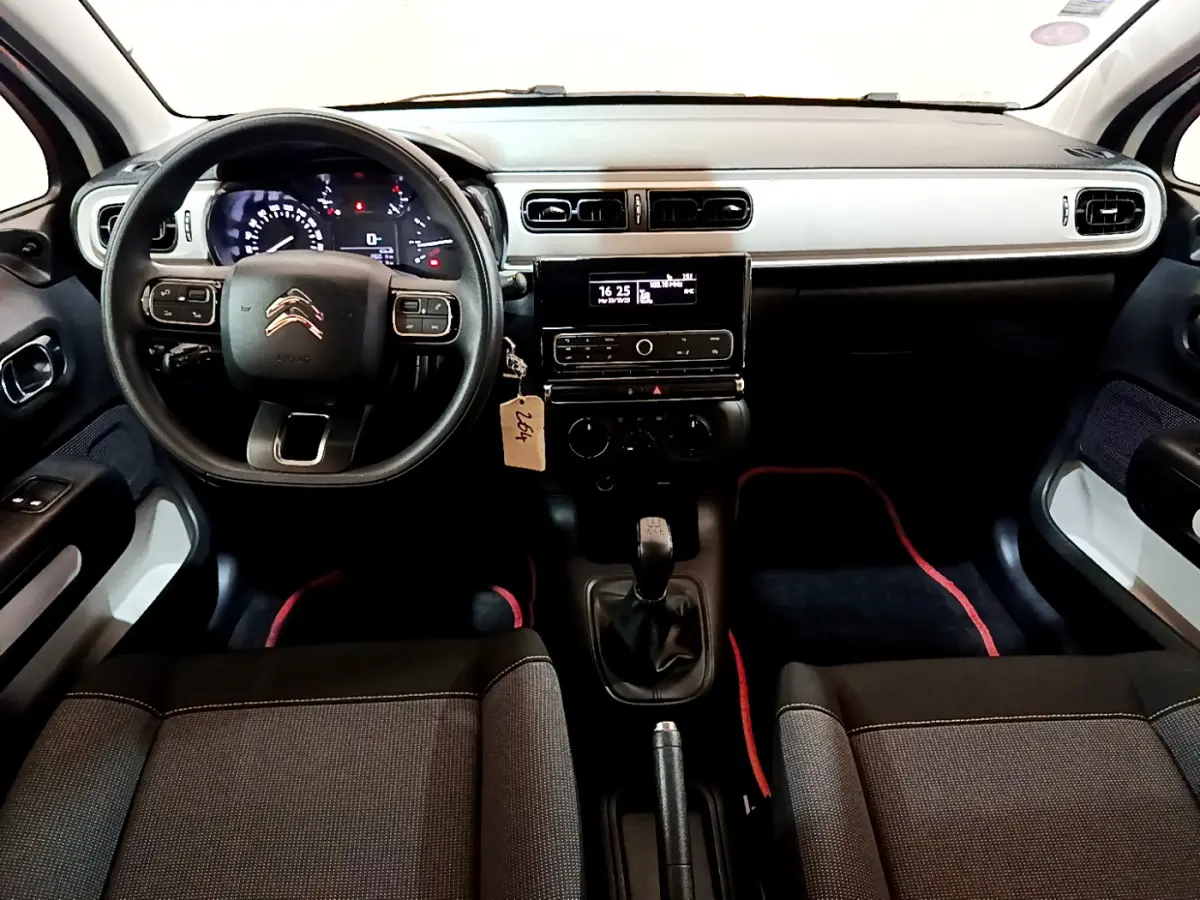 Vue intérieure avant de la Citroën C3 blanche 2018, tableau de bord noir et gris avec volant multifonction et boîte manuelle.