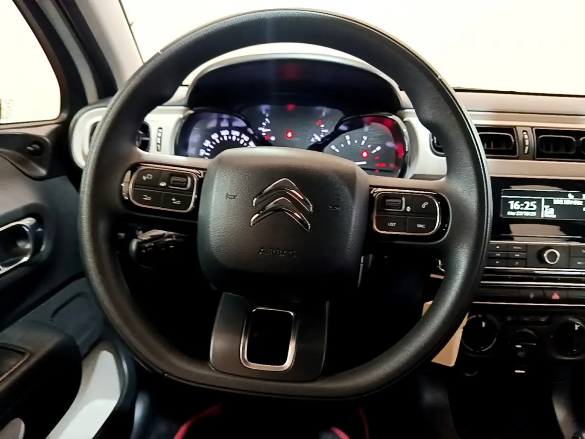 Vue intérieure centrée sur le volant noir de la Citroën C3 PureTech 68 BVM Live avec tableau de bord et console visibles.