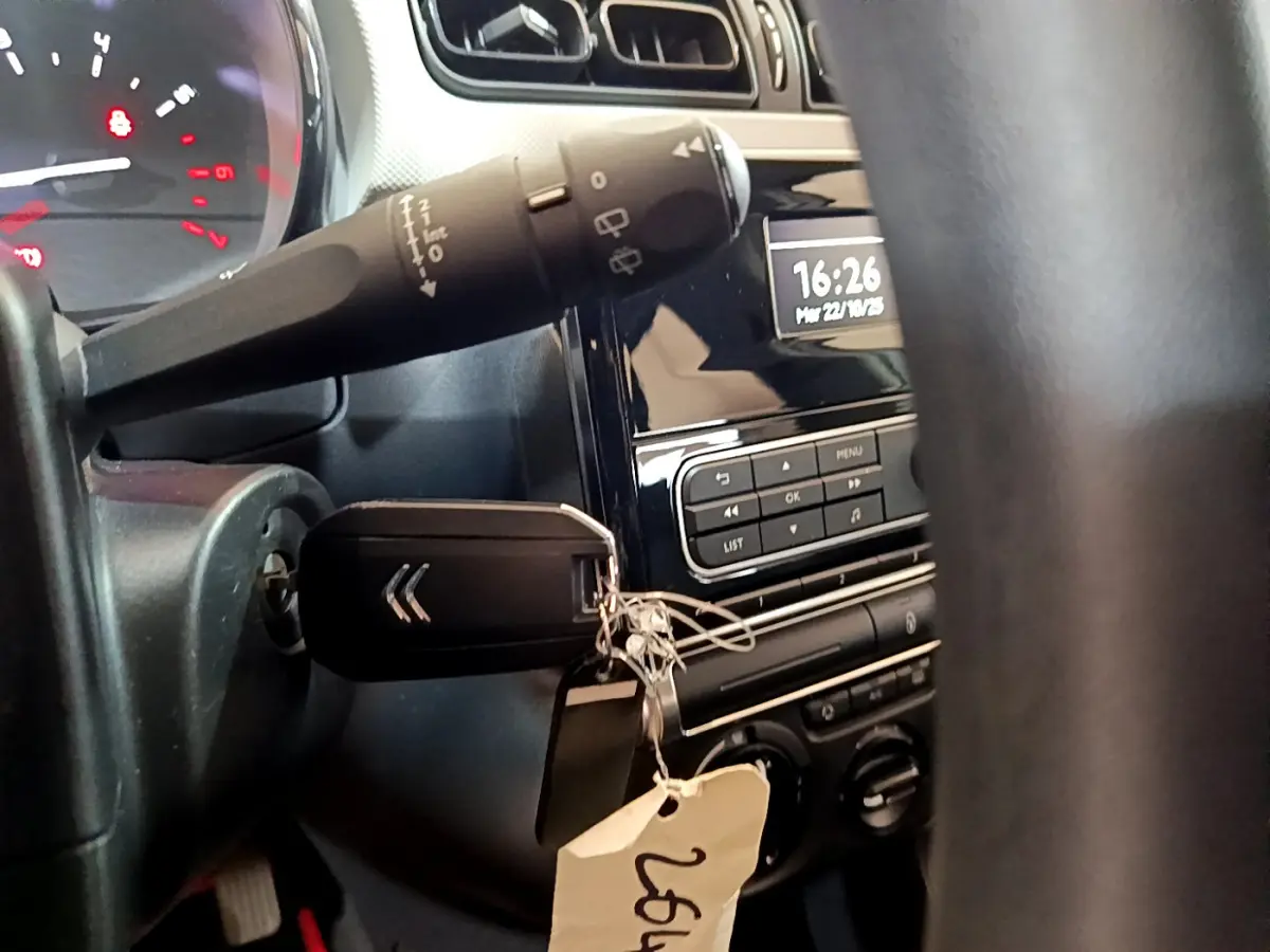 Vue rapprochée de l’intérieur de la Citroën C3 blanche 2018, clé dans le contact et tableau de bord avec horloge digitale.