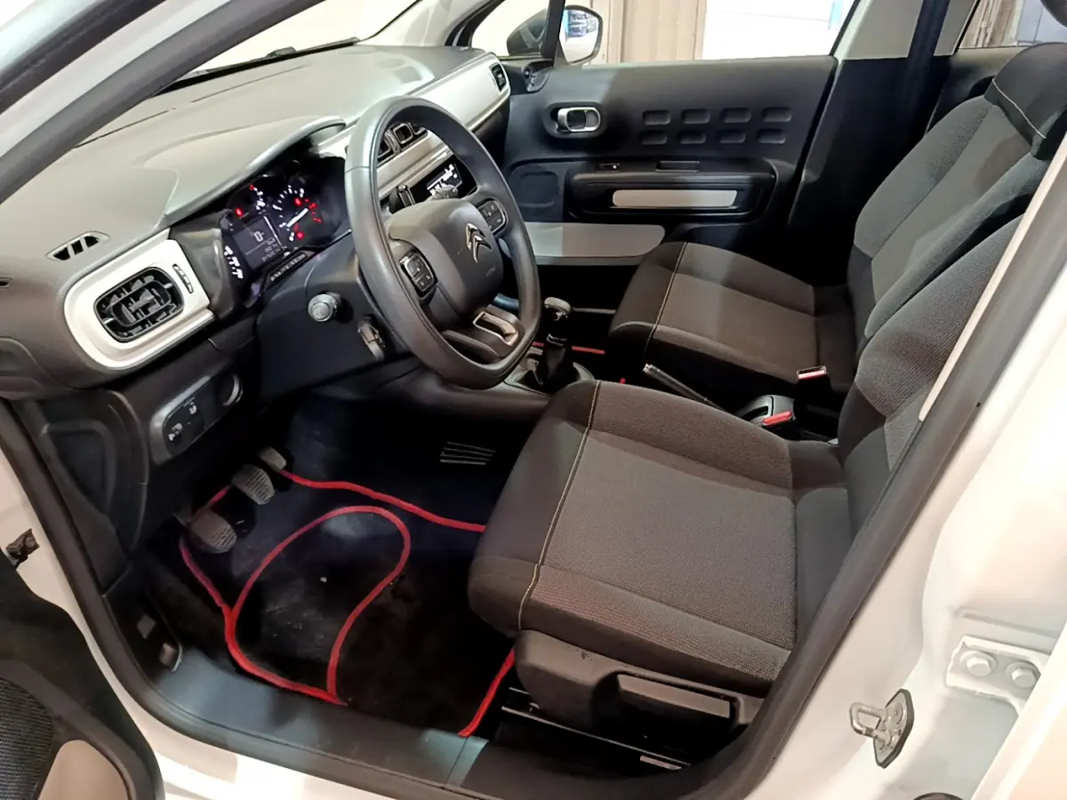 Intérieur avant droit d'une Citroën C3 blanche 2018, montrant le volant, tableau de bord et sièges noirs.