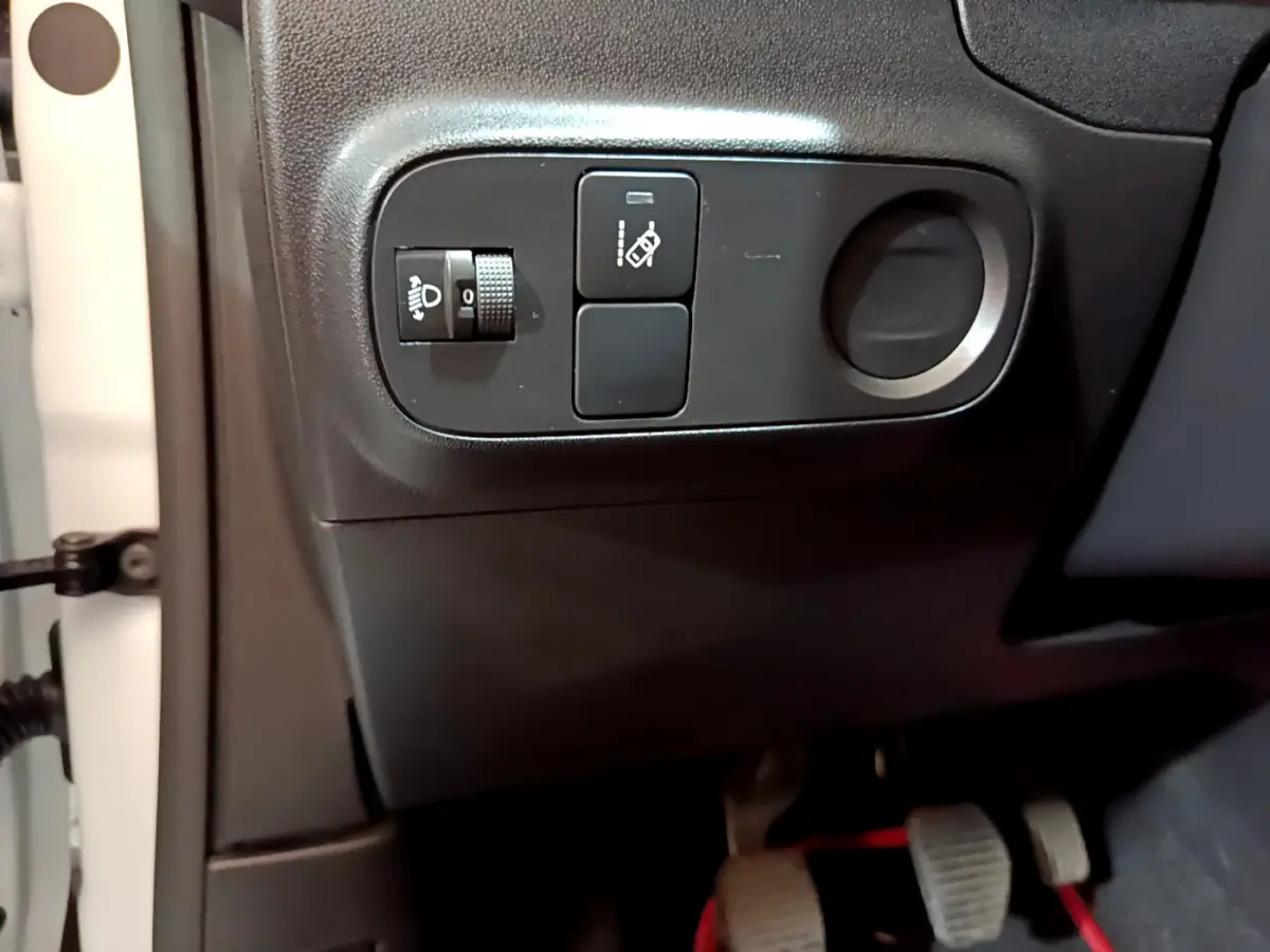 Gros plan sur les commandes de réglage des phares et d'assistance au freinage du côté gauche d'une Citroën C3 blanche 2018.
