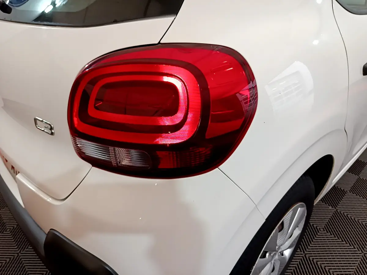 Gros plan sur le feu arrière droit rouge d'une Citroën C3 blanche de 2018, avec logo et partie latérale visible.