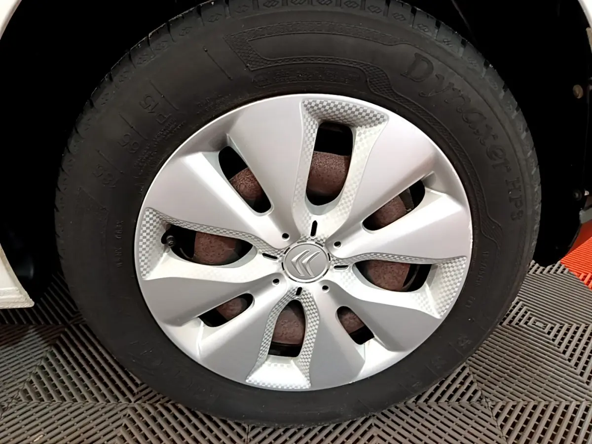 Gros plan sur la roue avant droite d'une Citroën C3 blanche, mettant en valeur la jante en alliage au design moderne.