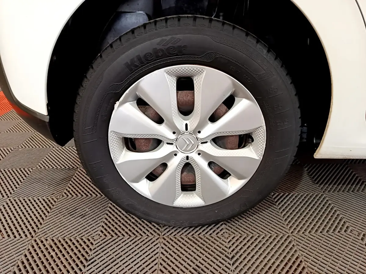 Gros plan sur la roue avant droite d'une Citroën C3 blanche de 2018 avec enjoliveur argenté et logo Citroën central.