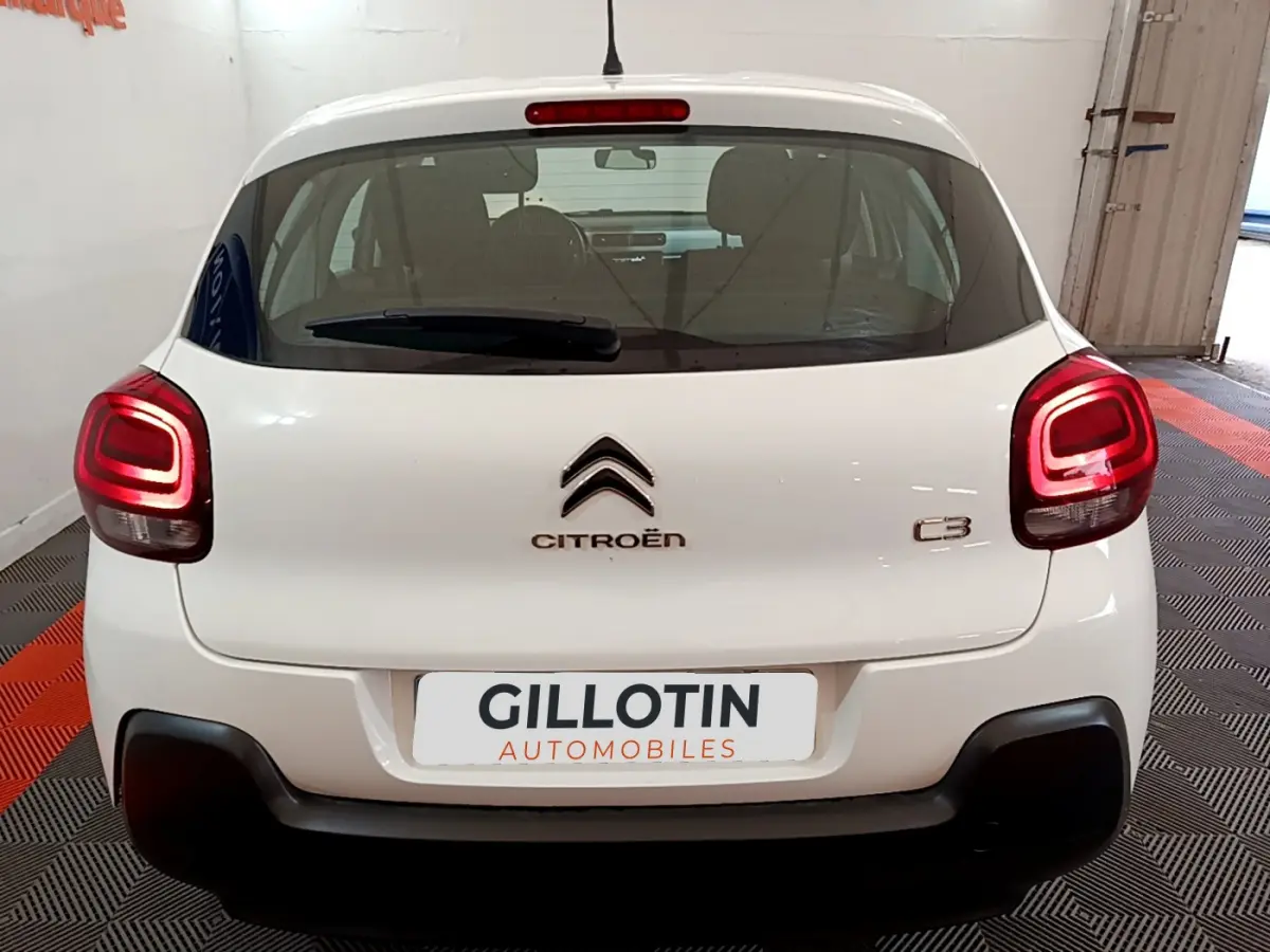 Vue arrière d'une Citroën C3 blanche de 2018 avec feux arrière allumés et logo centré sur le hayon.