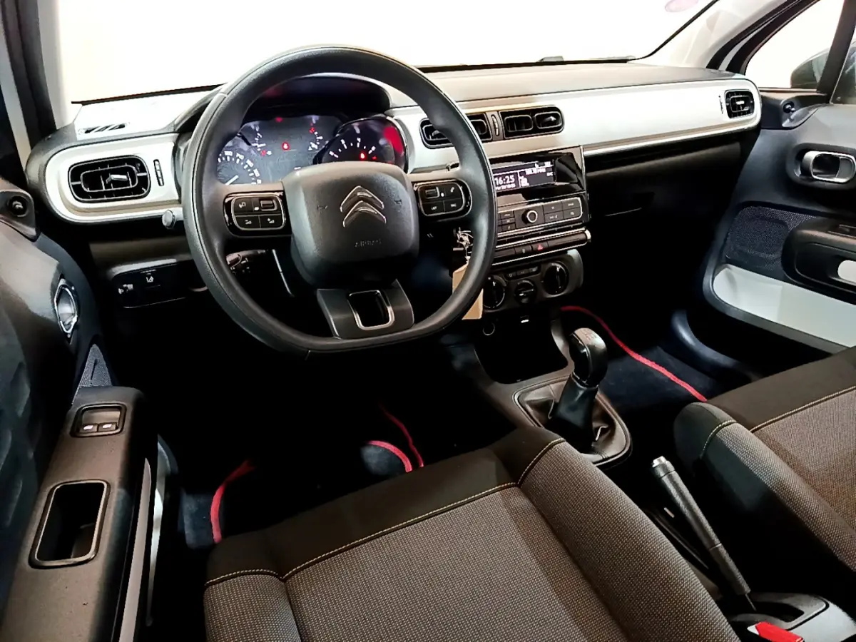 Intérieur avant de la Citroën C3 blanche 2018, vue côté conducteur avec tableau de bord et boîte manuelle visibles.