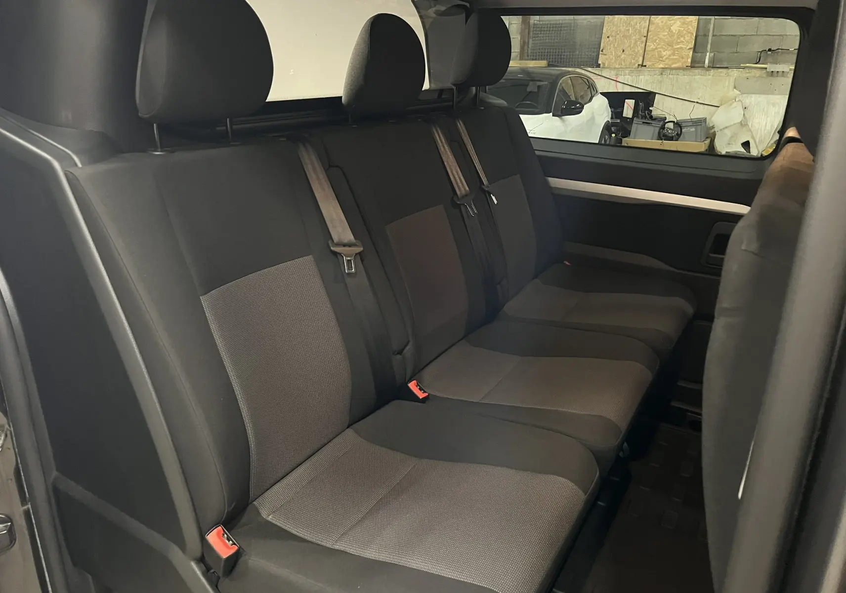 Vue intérieure côté droit des sièges arrière noirs et gris de l’Opel Vivaro cabine approfondie 2023, avec cloison vitrée.