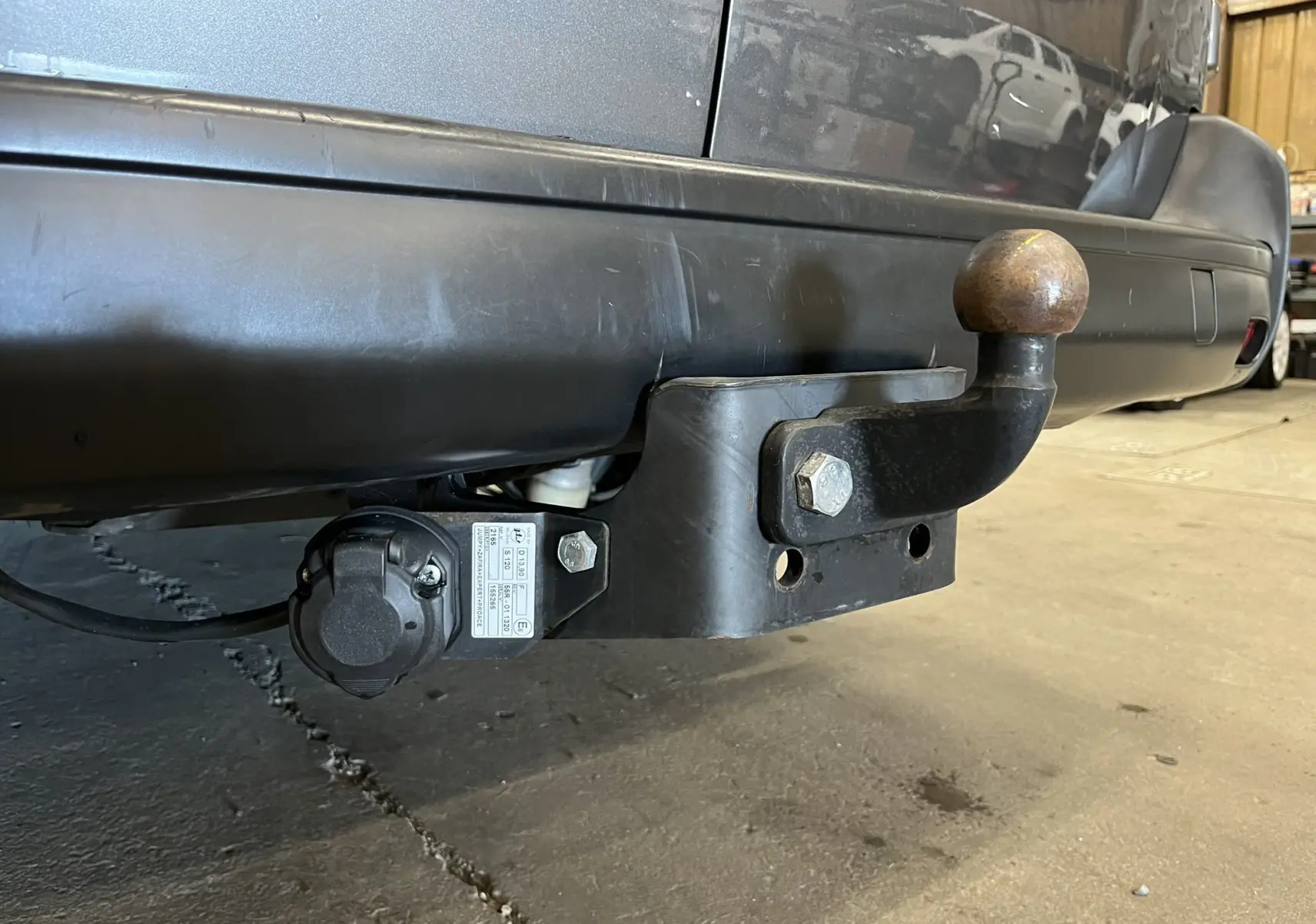 Gros plan sur l'attelage arrière noir d'un Opel Vivaro gris, avec prise électrique visible sous le pare-chocs.