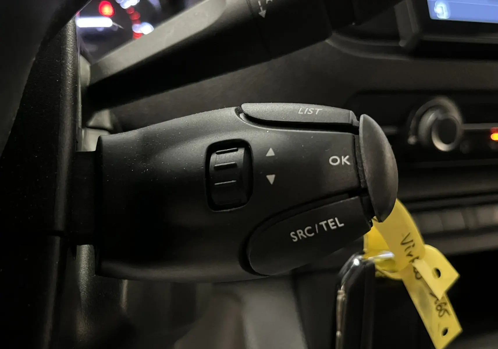 Gros plan sur la commande au volant noir de l'Opel Vivaro cabine approfondie, avec tableau de bord partiellement visible en arrière-plan.