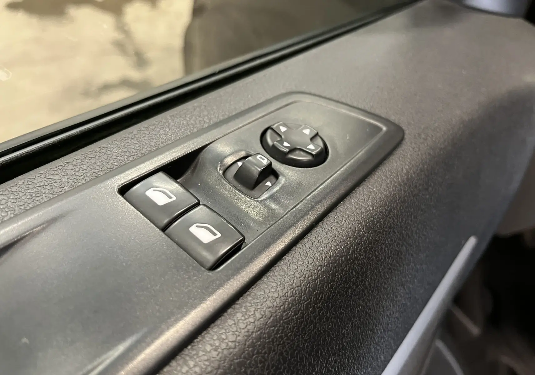 Gros plan sur les commandes de réglage des rétroviseurs et des vitres côté conducteur de l'Opel Vivaro XL gris 2023.