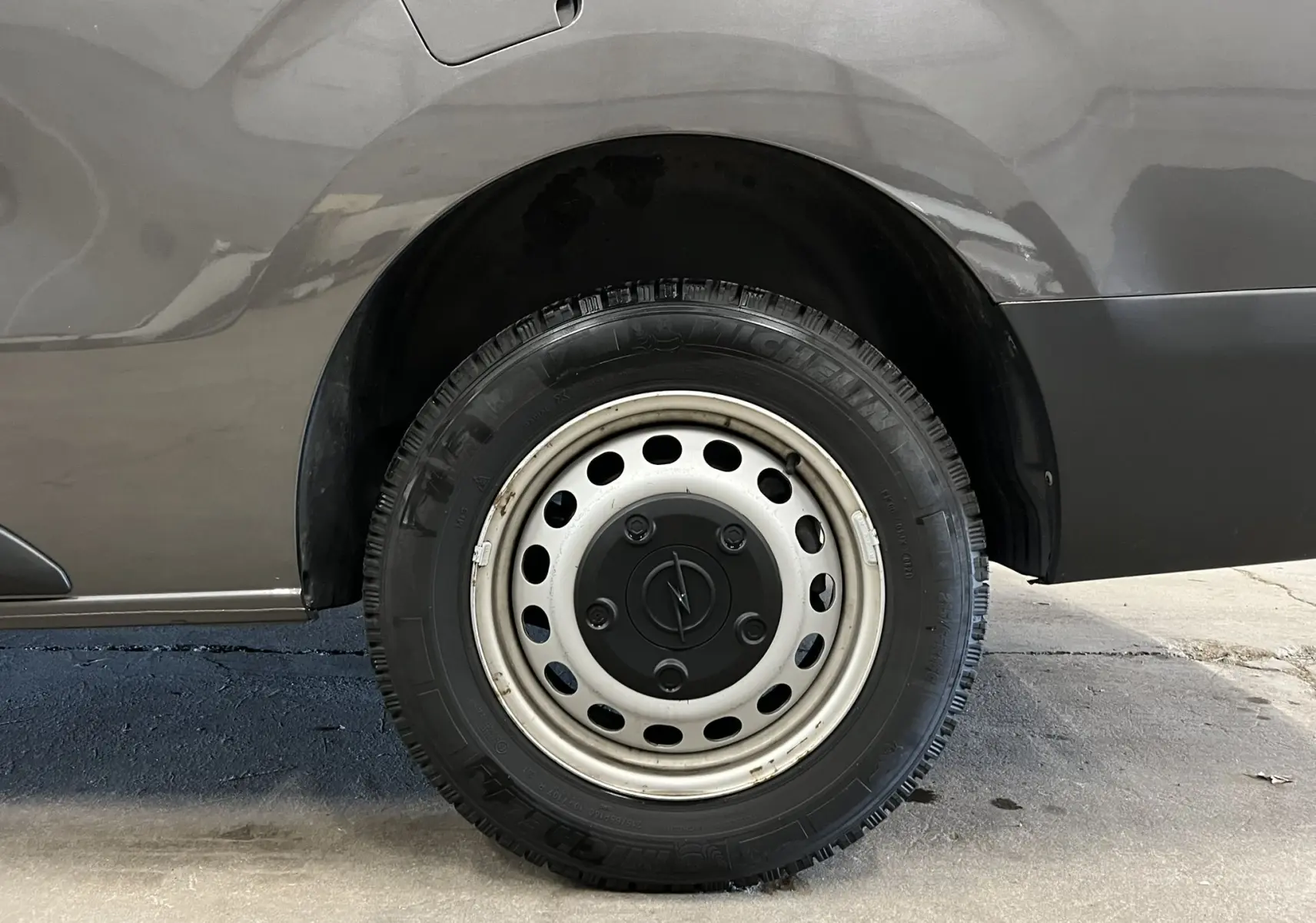 Gros plan sur la roue arrière droite grise d’un Opel Vivaro Cabine Approfondie XL 2023 avec jante acier et logo Opel central.