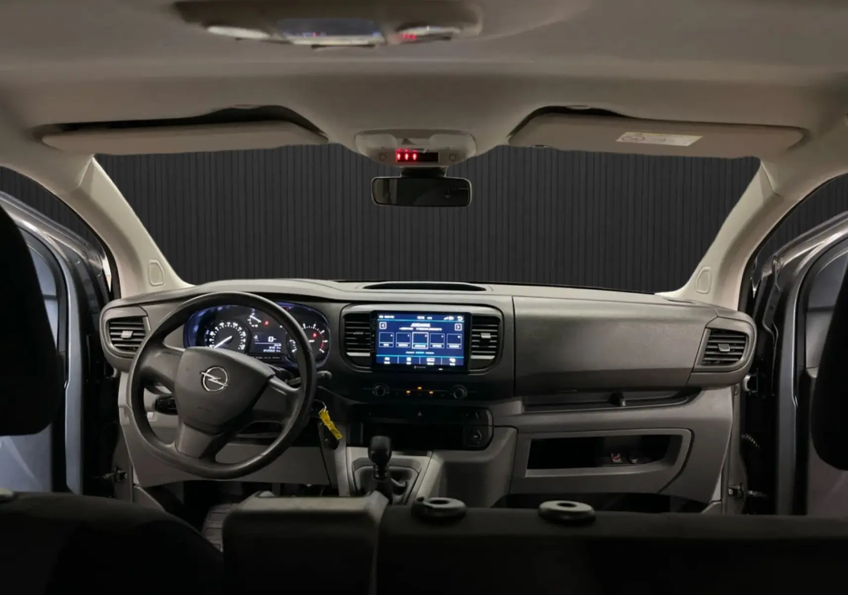 Vue intérieure avant de l’Opel Vivaro XL gris 2023, tableau de bord avec écran tactile et volant à gauche.