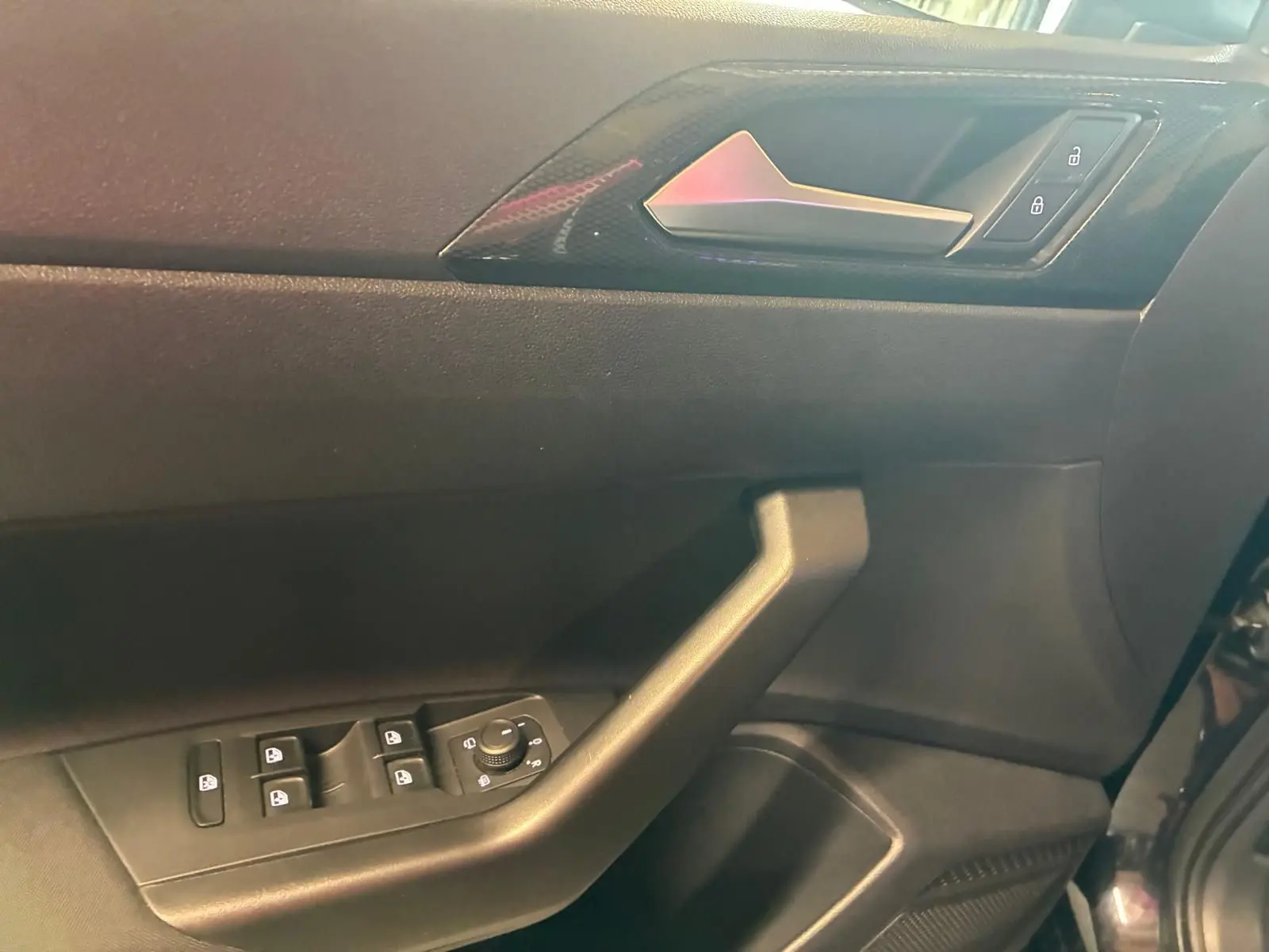 Vue rapprochée de la porte avant gauche noire d'une Volkswagen Polo 2022, avec commandes électriques et poignée intégrée.