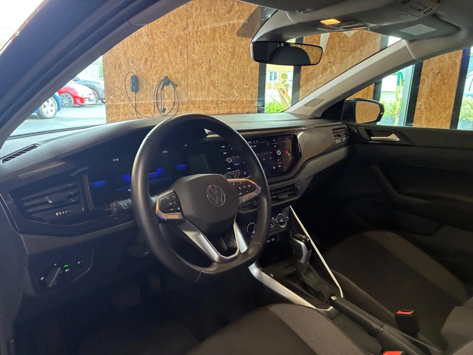 Vue intérieure côté conducteur de la Volkswagen Polo noire 2022, volant multifonctions et tableau de bord moderne.