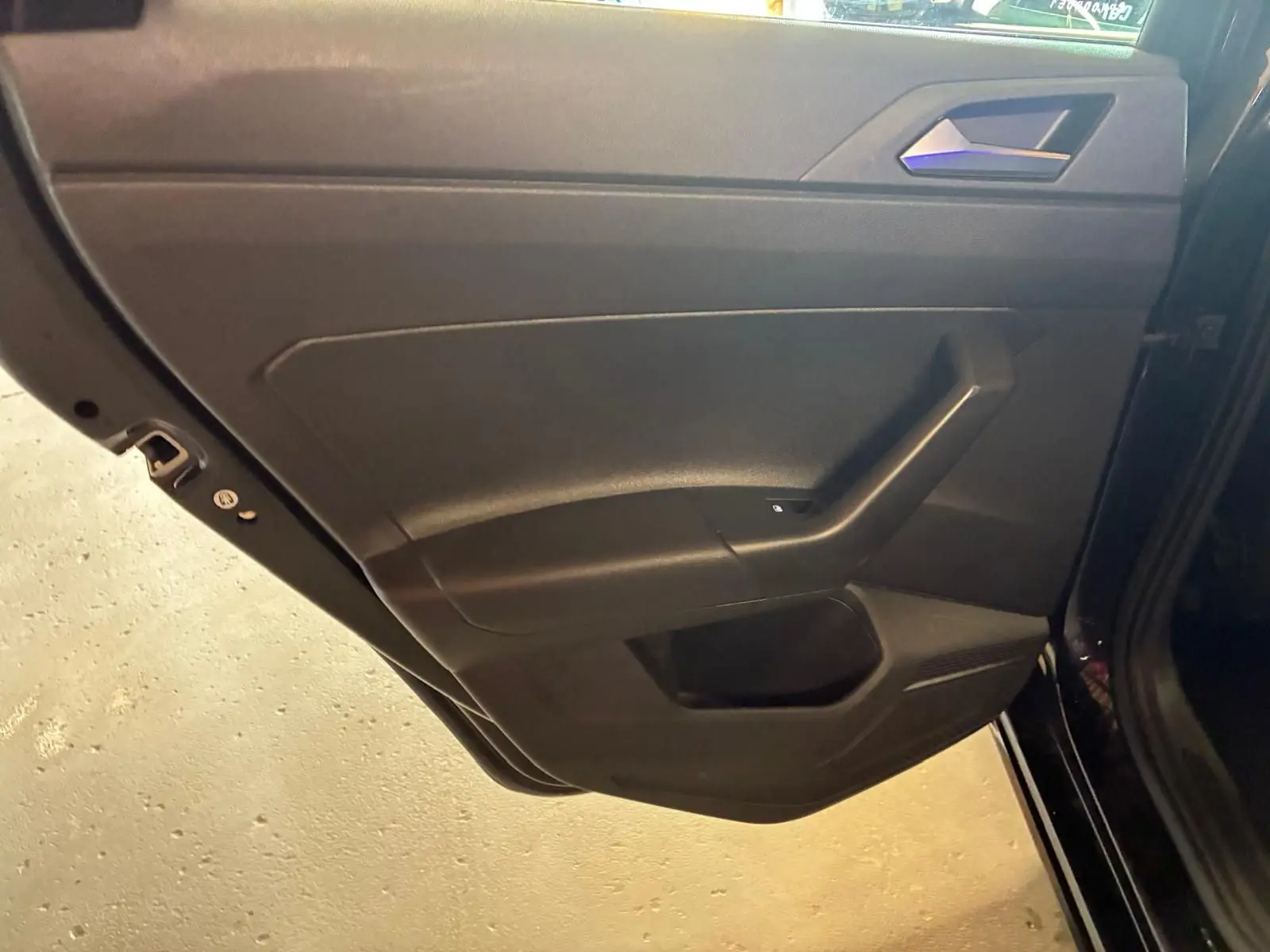 Vue intérieure de la porte arrière gauche noire du Volkswagen Polo 2022 avec poignée intégrée et commande de vitre électrique.