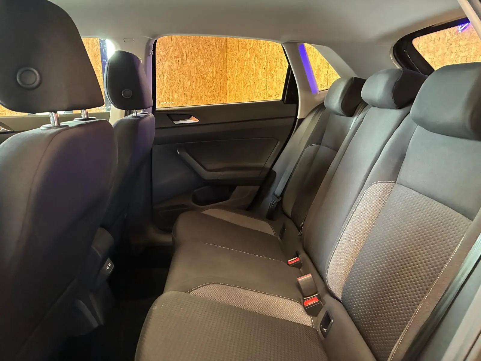Vue intérieure de la banquette arrière gris noir en tissu de la Volkswagen Polo 2022, côté droit avec appuis-tête et ceintures.