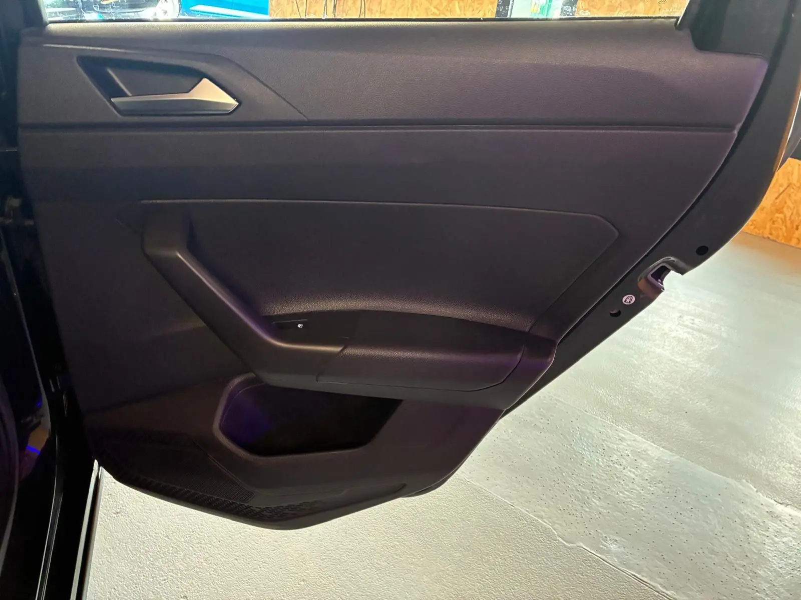 Vue rapprochée de la porte intérieure côté gauche noire de la Volkswagen Polo 1.0 TSI 95 DSG7 Life 2022 avec poignée intégrée.