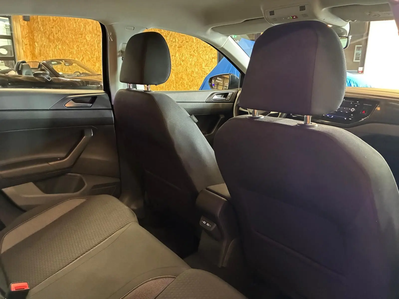 Vue intérieure arrière droite de la Volkswagen Polo noire 2022, sièges tissu gris-noir et console centrale avec ports USB-C.