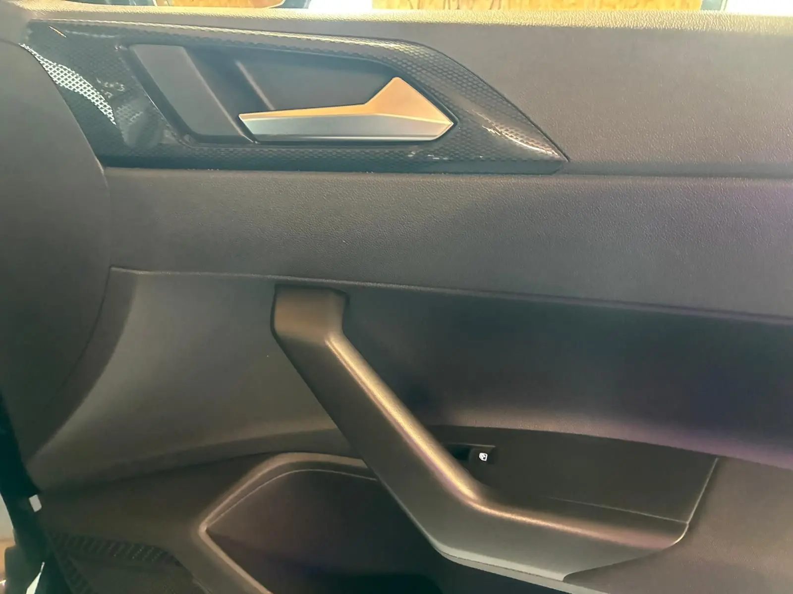 Gros plan sur la poignée de porte côté gauche intérieure d'une Volkswagen Polo noire avec finition tissu gris-noir.