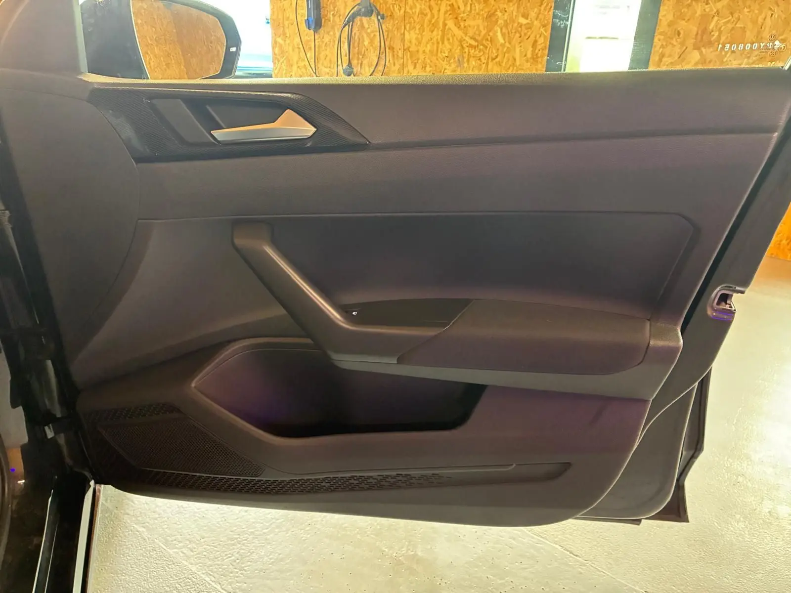 Vue rapprochée de la porte avant gauche noire d’une Volkswagen Polo 2022, avec poignée argentée et panneau noir mat.