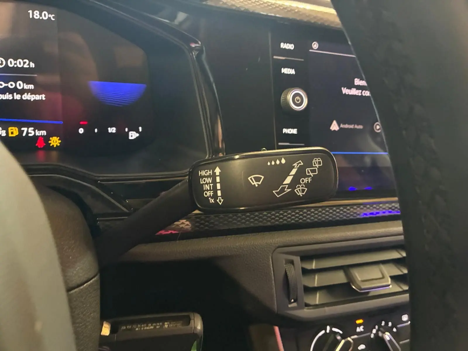 Gros plan sur la commande d’essuie-glace à gauche du volant dans l’habitacle gris noir d’une Volkswagen Polo noire 2022.