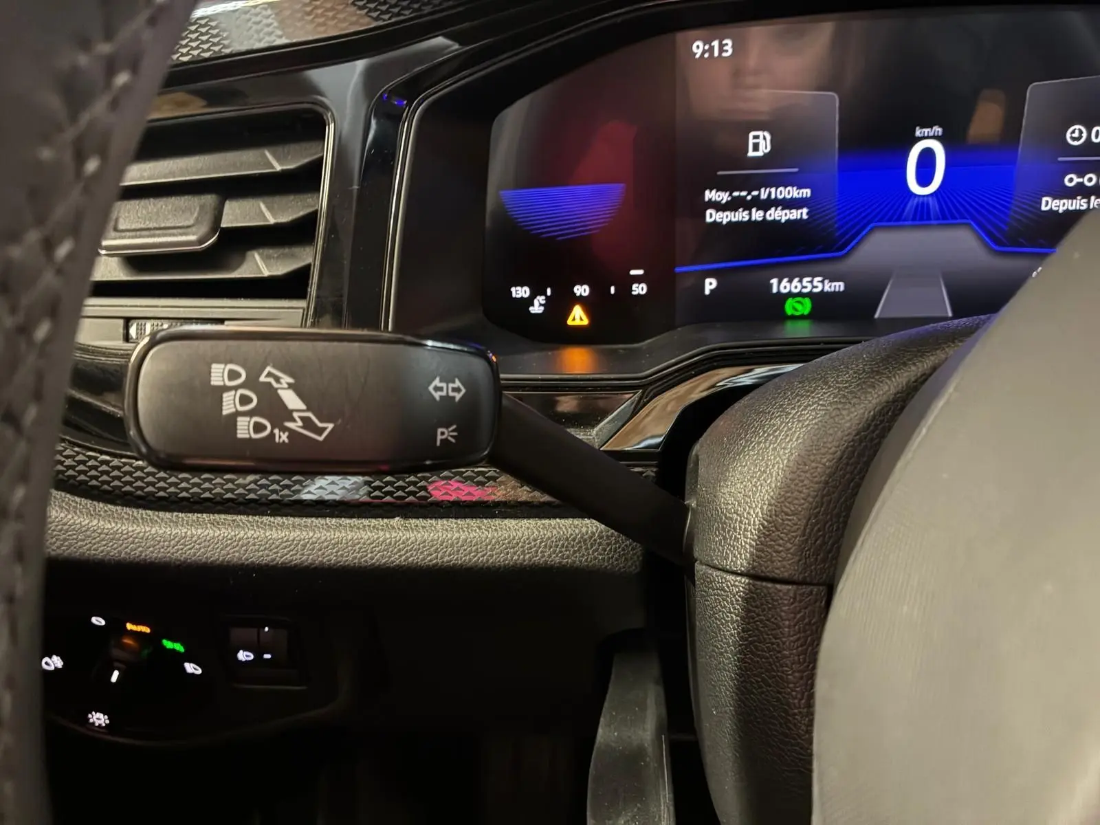 Gros plan sur le combiné d'instruments numérique et la commande de feux au volant d'une Volkswagen Polo noire de 2022.