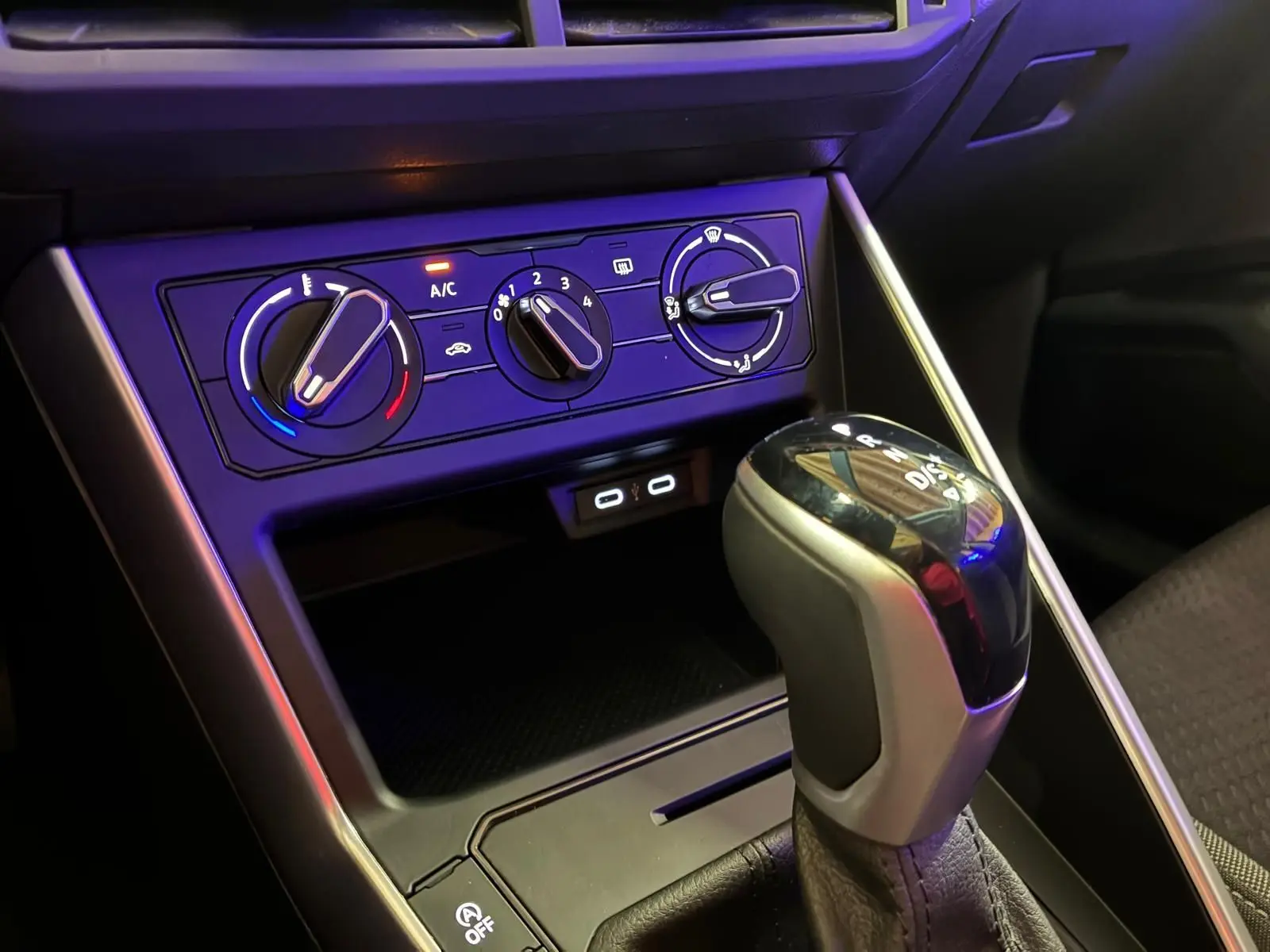 Gros plan intérieur sur la console centrale noire de la Volkswagen Polo 1.0 TSI 95 DSG7 Life avec commandes climatisation et levier de vitesse automatique.