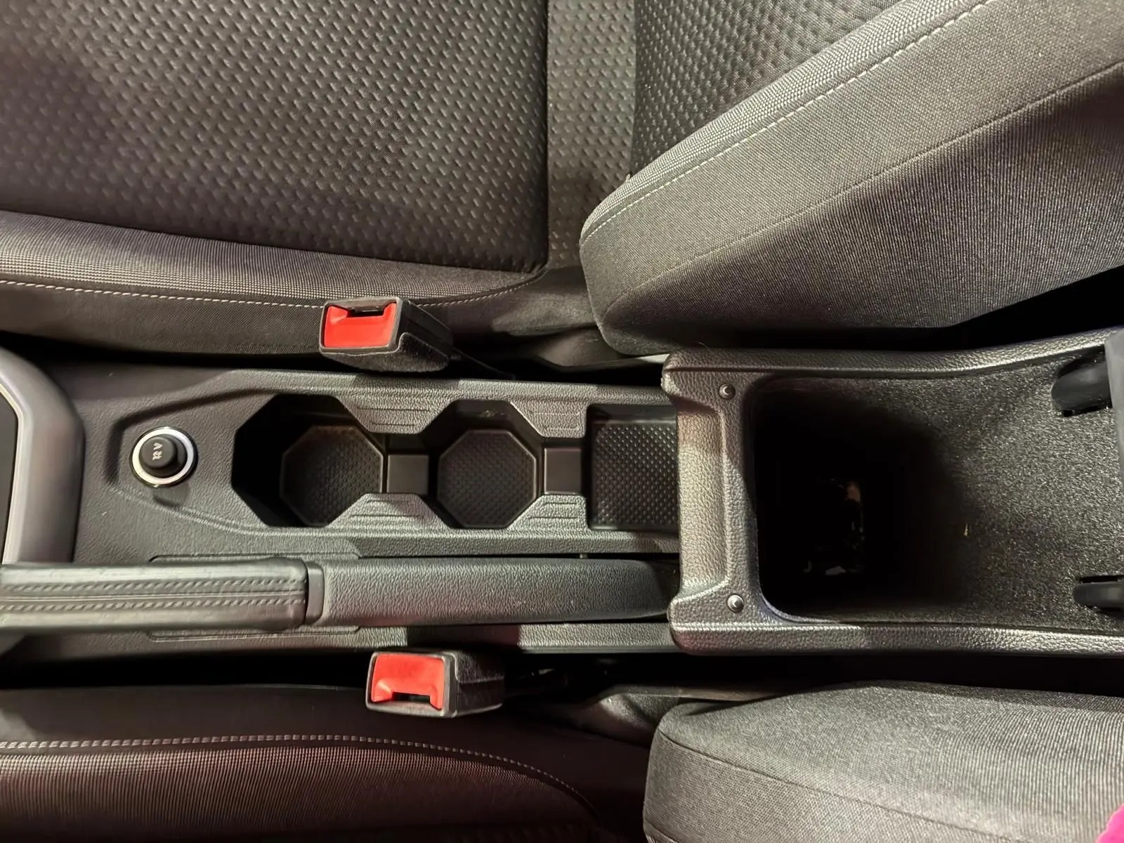 Vue rapprochée de la console centrale noire avec porte-gobelets et frein à main entre les sièges tissu gris foncé du Volkswagen Polo 2022.