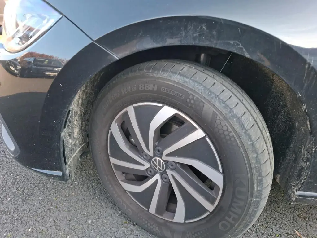 Gros plan sur la roue avant gauche noire d'une Volkswagen Polo 1.0 TSI 95 DSG7 Life avec jante alliage et carrosserie noire.