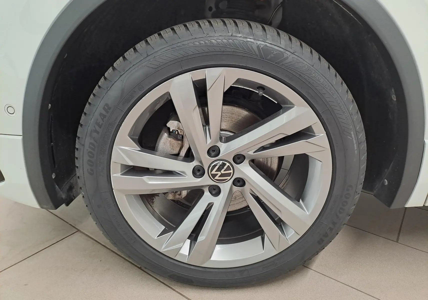 Gros plan sur la roue avant droite du Volkswagen Tiguan Allspace blanc pur 2023 avec jante alliage R-Line et pneu Goodyear.