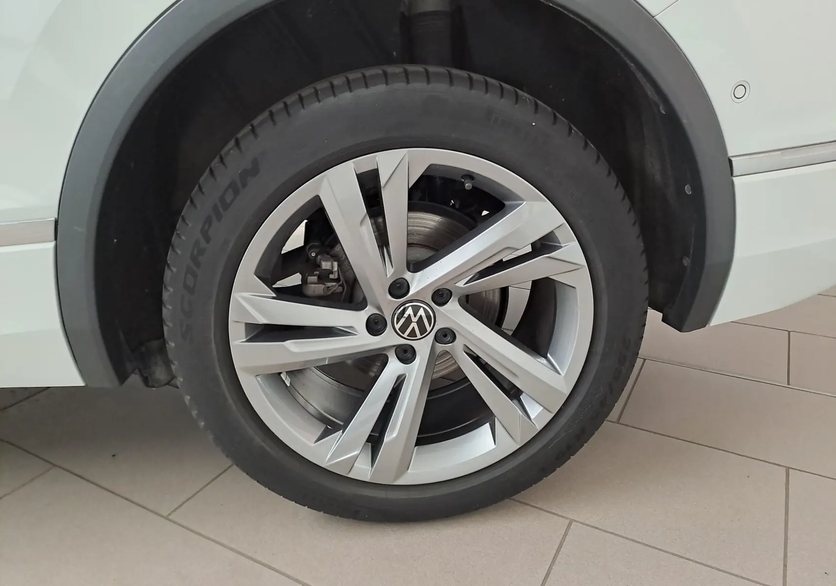 Gros plan sur la roue avant droite du Volkswagen Tiguan Allspace blanc pur 2023 avec jante alliage R-Line distinctive.