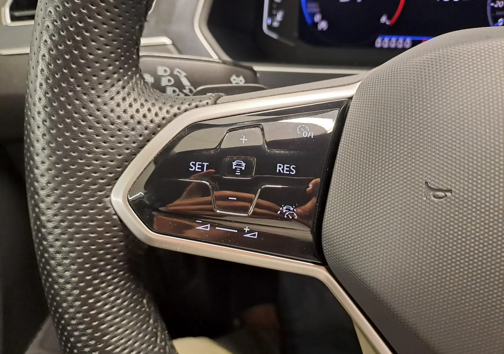 Gros plan sur les commandes au volant côté gauche du Volkswagen Tiguan Allspace blanc, version R-Line 2023.