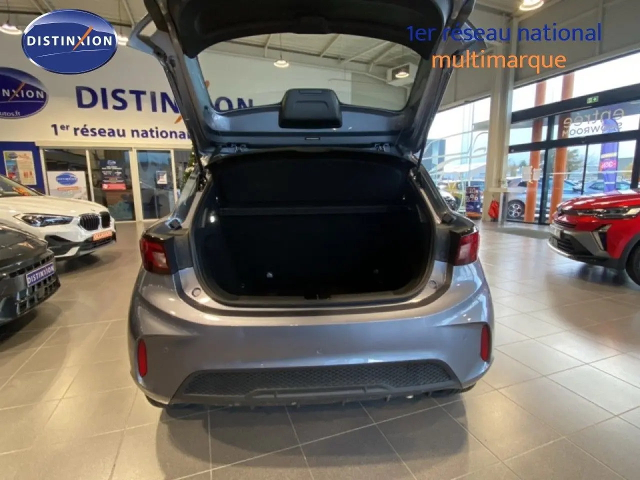 Vue arrière du MG3 1.5 Hybrid 195ch Comfort en gris métallisé Hampstead avec coffre ouvert dans un showroom.