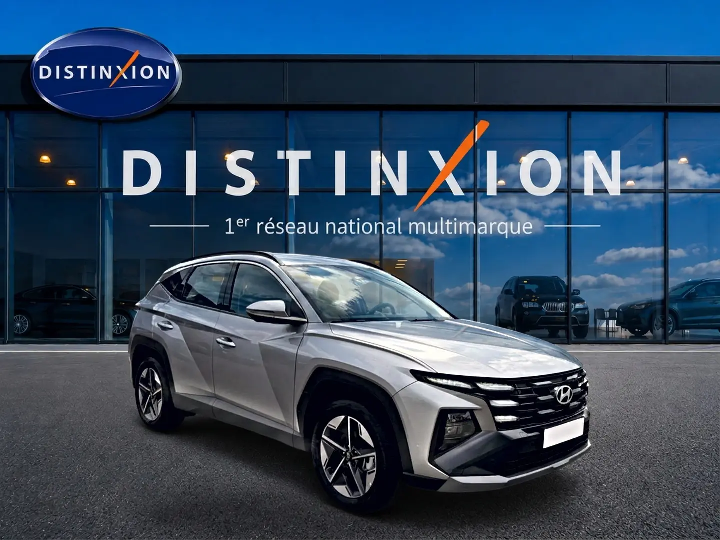 Hyundai Tucson gris shimmering vu en 3/4 avant droit, avec calandre noire et jantes alu 18 pouces.