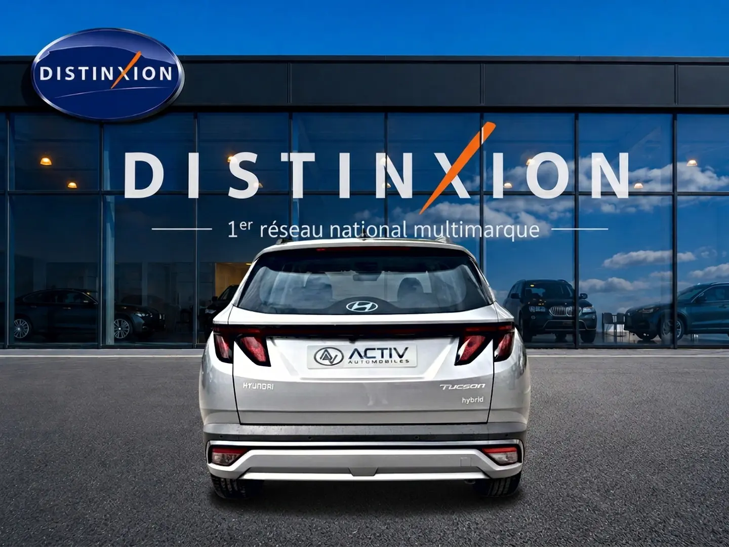 Vue arrière d'un Hyundai Tucson gris shimmering 2026 avec feux LED et logo Activ devant une vitrine Distinxion.